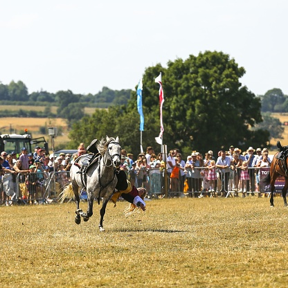 blakesley, United Kingdom – August 08, 2022: A woman falling from a horse during an agricultural show with the crowd in the blurred background