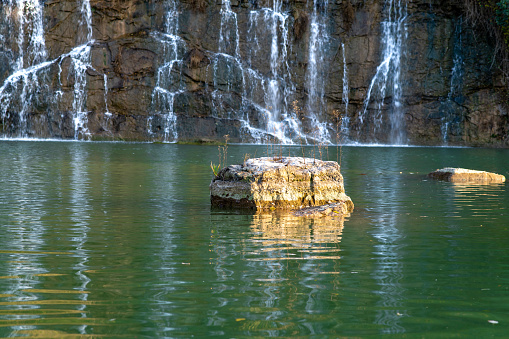 A beautiful view of a rock in a lake and silky waterfall
