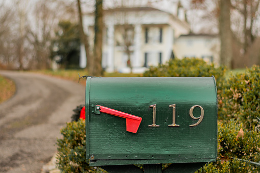 Closeup of the green mailbox in the street with address numbers.