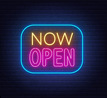 Now Open neon sign in frame on brick wall background .