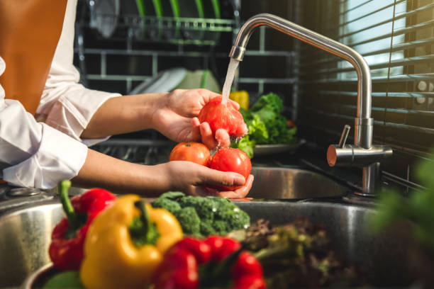 キッチンでトマト新鮮な野菜を洗うメイドの手は健康的な食べ物を準備します - cleaning domestic kitchen clean chef ストックフォトと画像