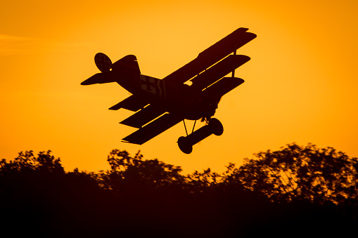 Old Fokker triplane flying into the sunset at an airshow in hahnweide, Germany