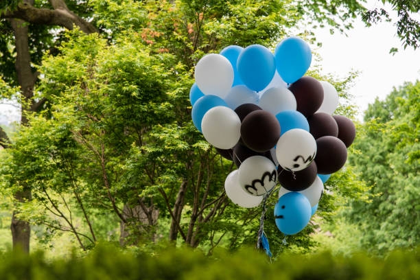 istock Bunch of blue, white, and black balloons in front of a tree 1461300938