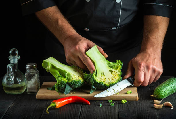 istock The chef cuts fresh Broccoli with a knife for salad on vintage kitchen table with fresh vegetables. Cooking and restaurant or cafe concept 1461302148