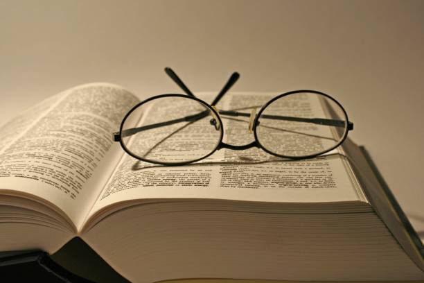 istock Open book and glasses on it with yellowish light 1461305099