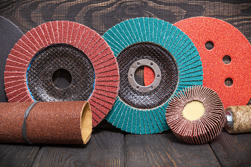 Big set of abrasive tools and multicolored sandpaper on wooden vintage black background, wizard is used for grinding items