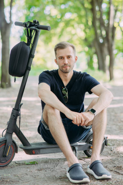 istock Young man sits on electric scooter in park. 1461310448