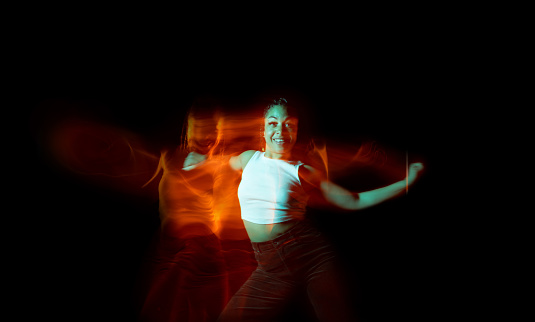 Young woman posing and dancing on black background