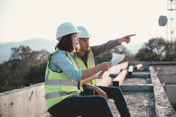 istock Two specialists inspect commercial, Industrial building construction site. Real estate project with civil engineer, designing commercial buildings on paper. Skyscraper concrete formwork frames. 1461313321