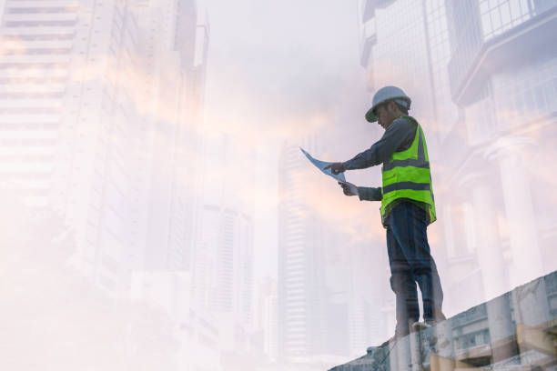 istock Double exposure image of engineer civil and construction worker with safety helmet and construction drawing against the background of surreal construction site in the night city or dark cityscape. 1461314218