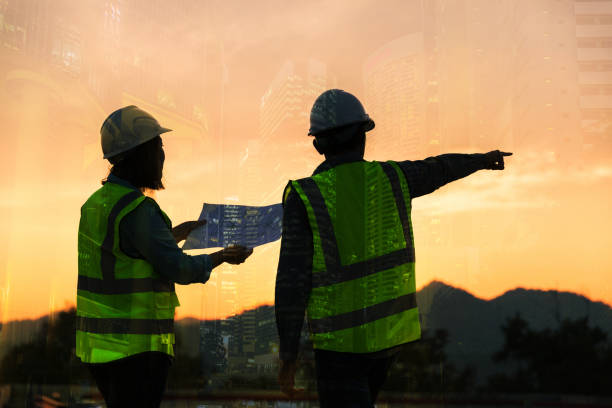 istock Double exposure image of engineer civil and construction worker with safety helmet and construction drawing against the background of surreal construction site in the night city or dark cityscape. 1461314319