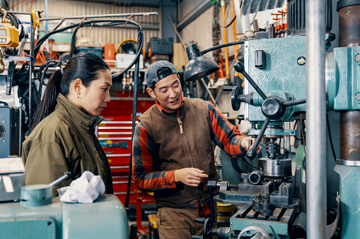 Two colleagues talking around machining equipment at a metal fabrication workshop in Japan