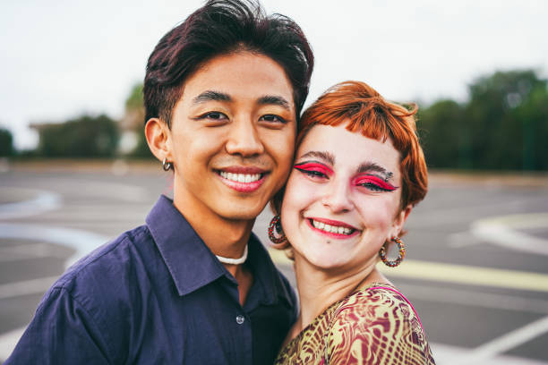 Young diverse friends having fun outdoor - Focus on gay asian guy wearing make-up stock photo