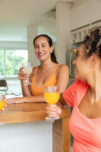 brazilian woman smiling and drinking juice with friends in the kitchen