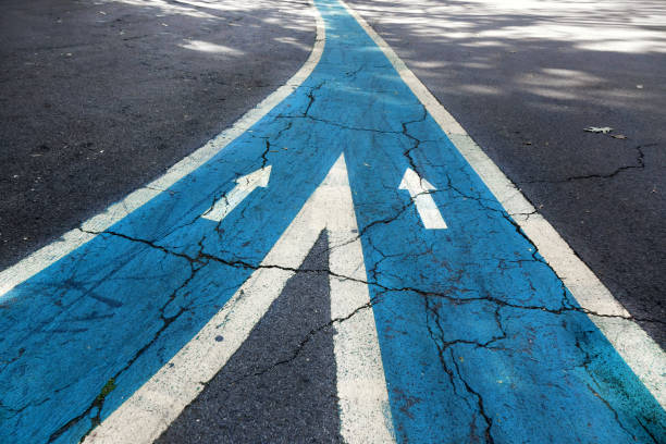 Merging asphalt road with arrow signs Close up arrow signs on asphalt city road middle of the road stock pictures, royalty-free photos & images