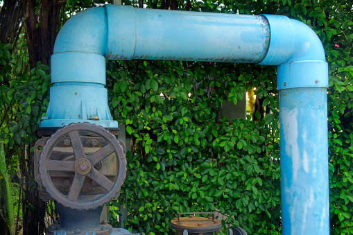 Old rusted iron pipe and control valve on house wall. Vintage rusty metal handle wheel and pipes