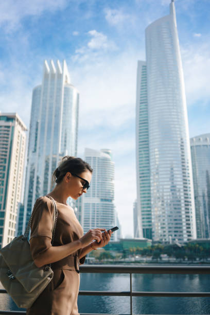 istock Woman using smartphone in front of the modern city background 1461321190