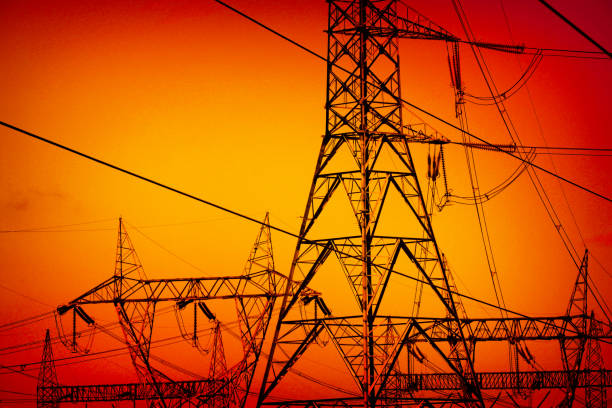 A tall powerline with a glowing sun in the sky