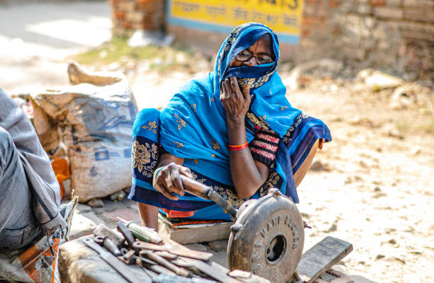 A female blacksmith was revving up a fire to burn hot iron. Used to hit and repair equipment made of iron along the sidewalk in Sarnath, India A female blacksmith was revving up a fire to burn hot iron. Used to hit and repair equipment made of iron along the sidewalk in Sarnath, India Revving stock pictures, royalty-free photos & images