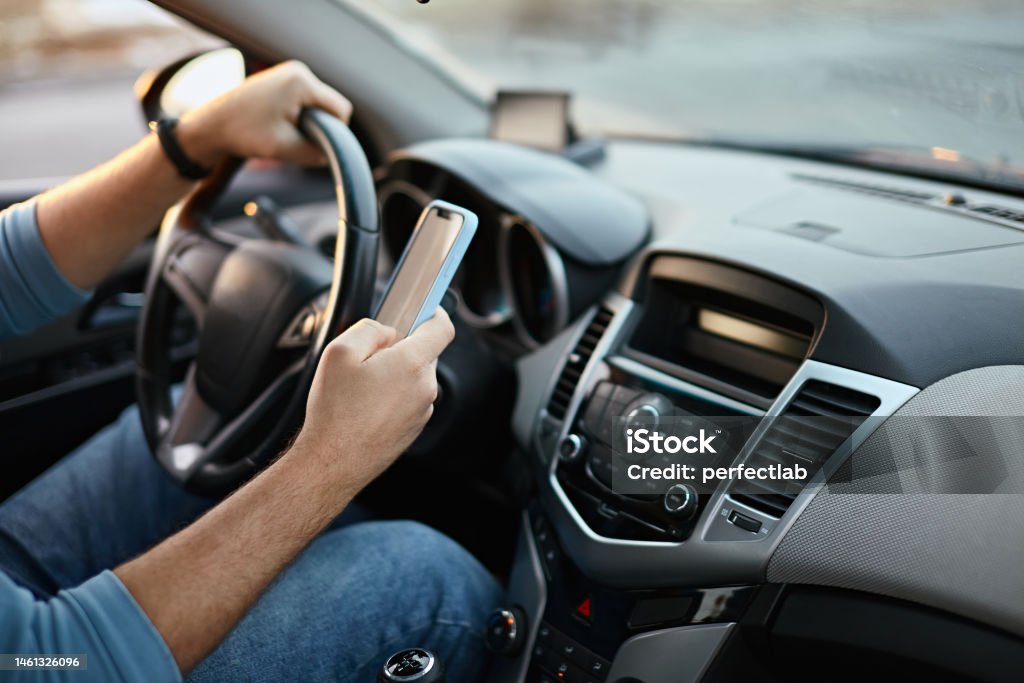 Hands of unrecognizable man driver using mobile phone while driving Hands of unrecognizable man driver using mobile phone while driving. Driving Stock Photo