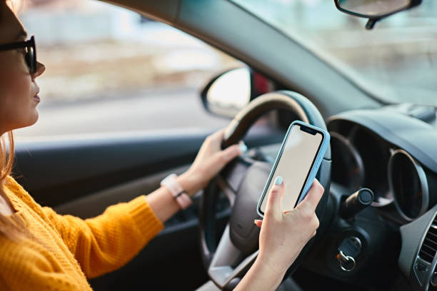 istock Woman driver using mobile phone screen blank mockup while driving distracted from the road 1461326295