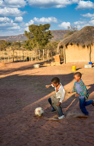 African village children playing football on the dirt in the yard