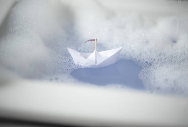 istock Small paper boat floats in the bathtub with bath foam 1461326502