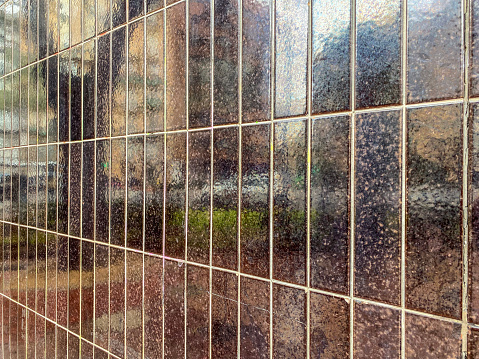 Buildings and city traffic reflecting on shiny dark tiled wall in the street in the city of Valencia, Spain