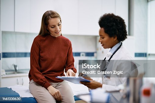 istock Happy woman going through her medical data with black female doctor at the clinic. 1461330630