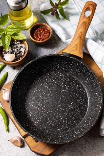 Empty skillet, vegetables, spices and herbs on gray stone background. Food cooking background with Frying pan.