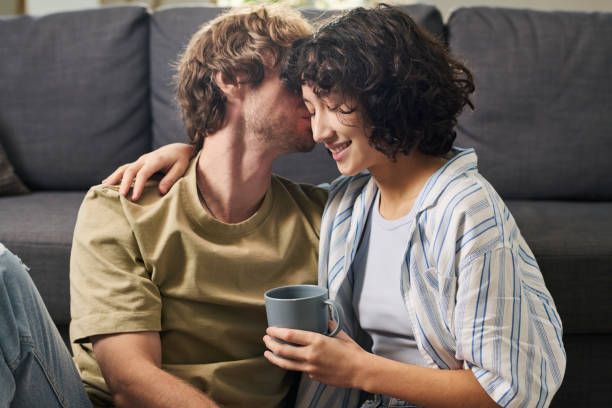 istock Young intercultural romantic couple enjoying home rest by couch 1461332113