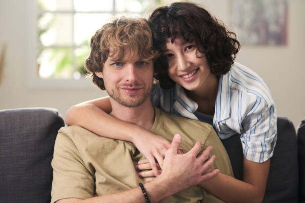 istock Young affectionate couple relaxing on couch and looking at camera 1461333597