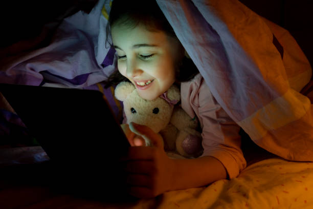istock Little girl using digital tablet in her bed at night 1461334086