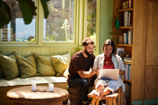 istock Young couple smiling while using a laptop in their living room 1461334089