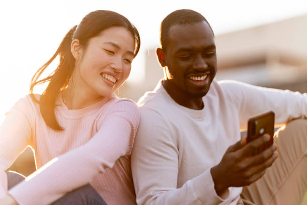 istock Couple having fun together in a public park using smart phone 1461334508