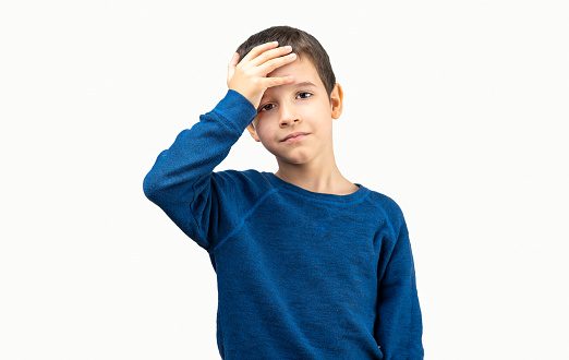 Stressed dark haired boy with hand on head, shocked with shame and surprise face, angry and frustrated. Fear and discomfort by mistake with white background.