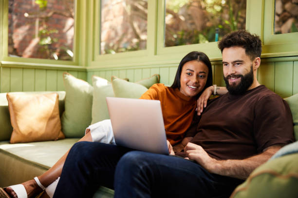 istock Smiling young couple using a laptop together on their sofa 1461335384