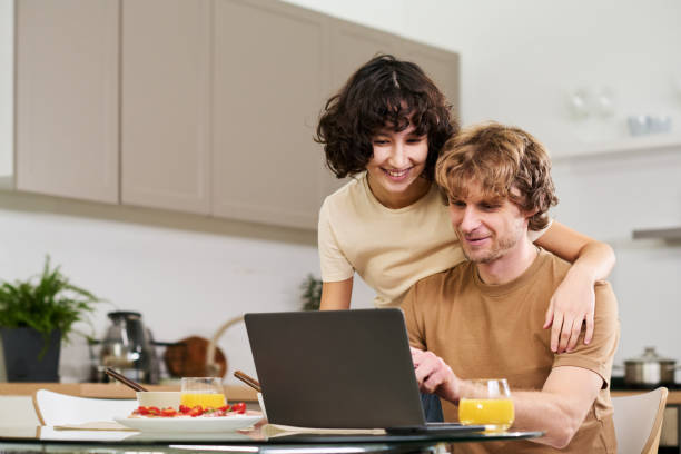 istock Happy young woman embracing her husband while both looking at laptop screen 1461335513