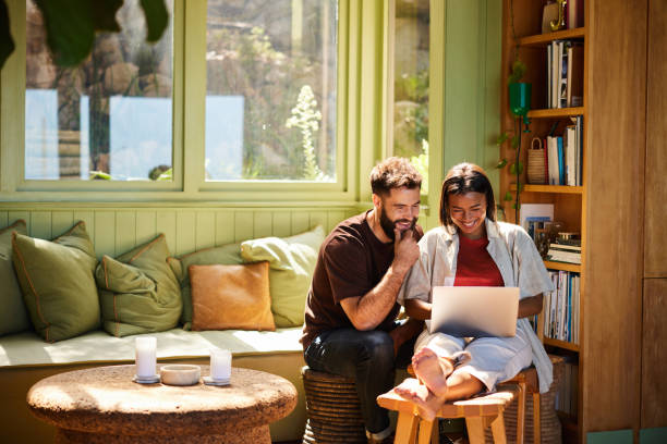 istock Smiling young couple using a laptop in their living room 1461335532