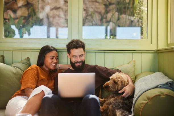 Smiling couple using a laptop while sitting with their dog at home