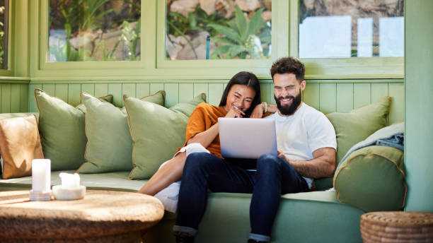 istock Laughing young couple watching something on a laptop on their sofa 1461336121
