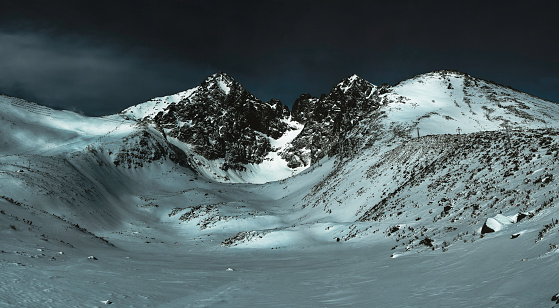 Panorama of the mountain snow-capped peaks in dark colors