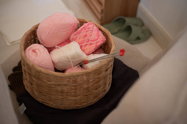 Pink and soft pastel woolen balls in basket with crochet hook