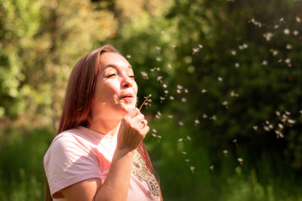 Woman enjoy at meadow full of dandelion seed on sunny springtime day in nature