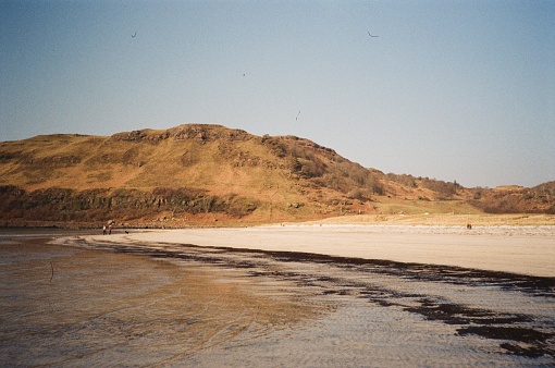 Vintage landscape of beach and hill with blue sky film photography Scotland