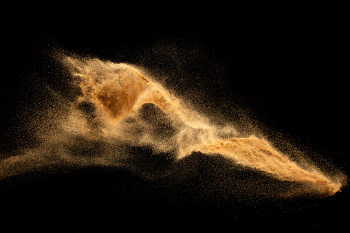 Dry river sand explosion.Brown color sand splash against black background.