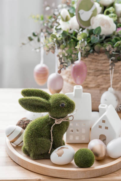 istock A beautiful postcard. The concept of the Bright Easter holiday. Flowers, rabbits, Easter eggs and Scandinavian white houses on a wooden table in a cozy living room. 1461342191