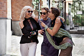 Three happy female friends laughing and cuddling outside. Lifestyle women portrait on city street