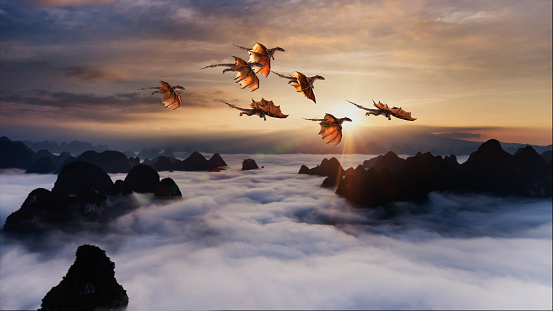 Flock of dragons flying over rolling clouds at sunrise