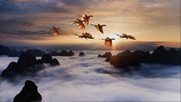 Flock of dragons flying over rolling clouds at sunrise stock photo